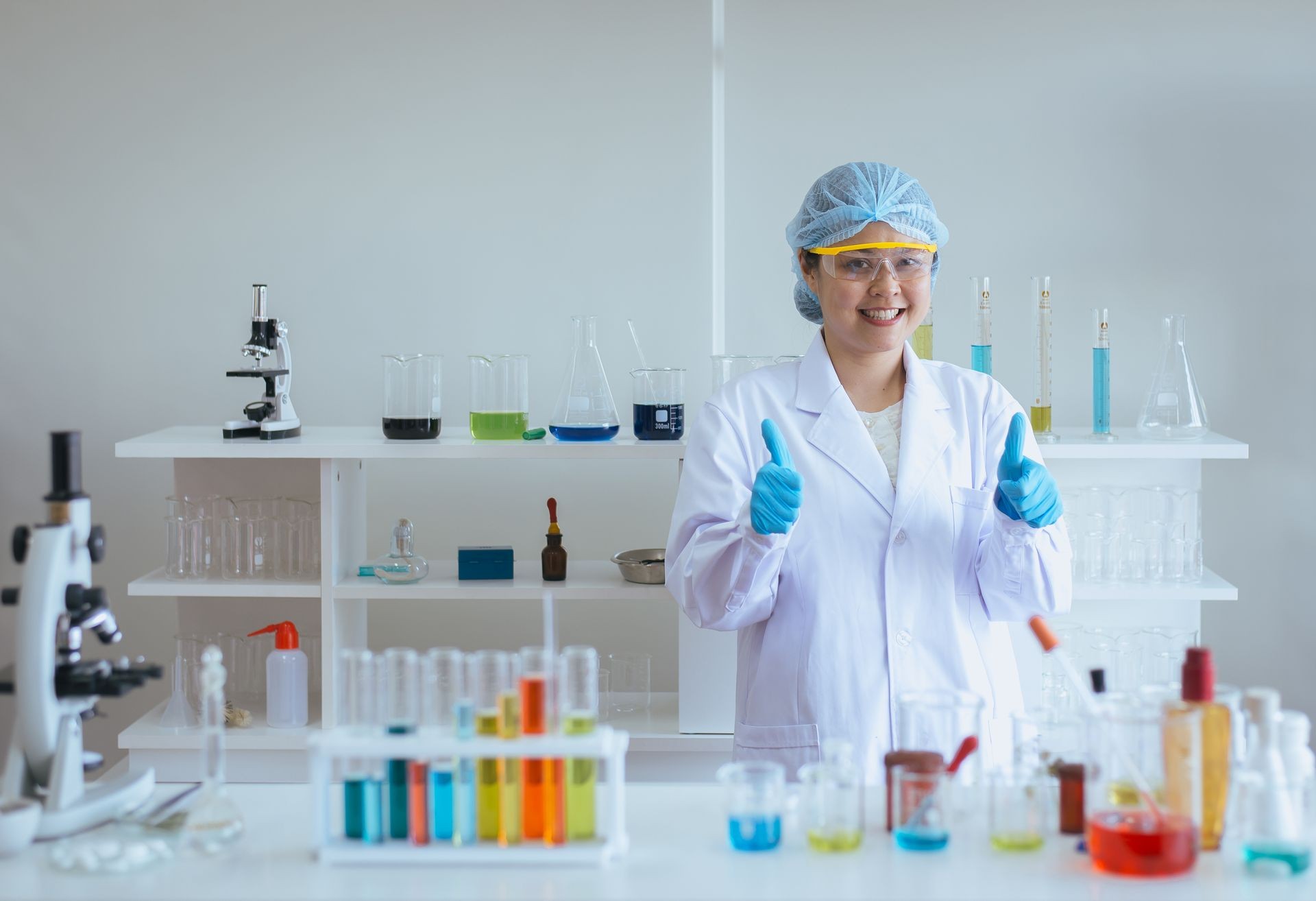 Happy scientist asian woman studying medical chemicals and showing thumb up in laboratory